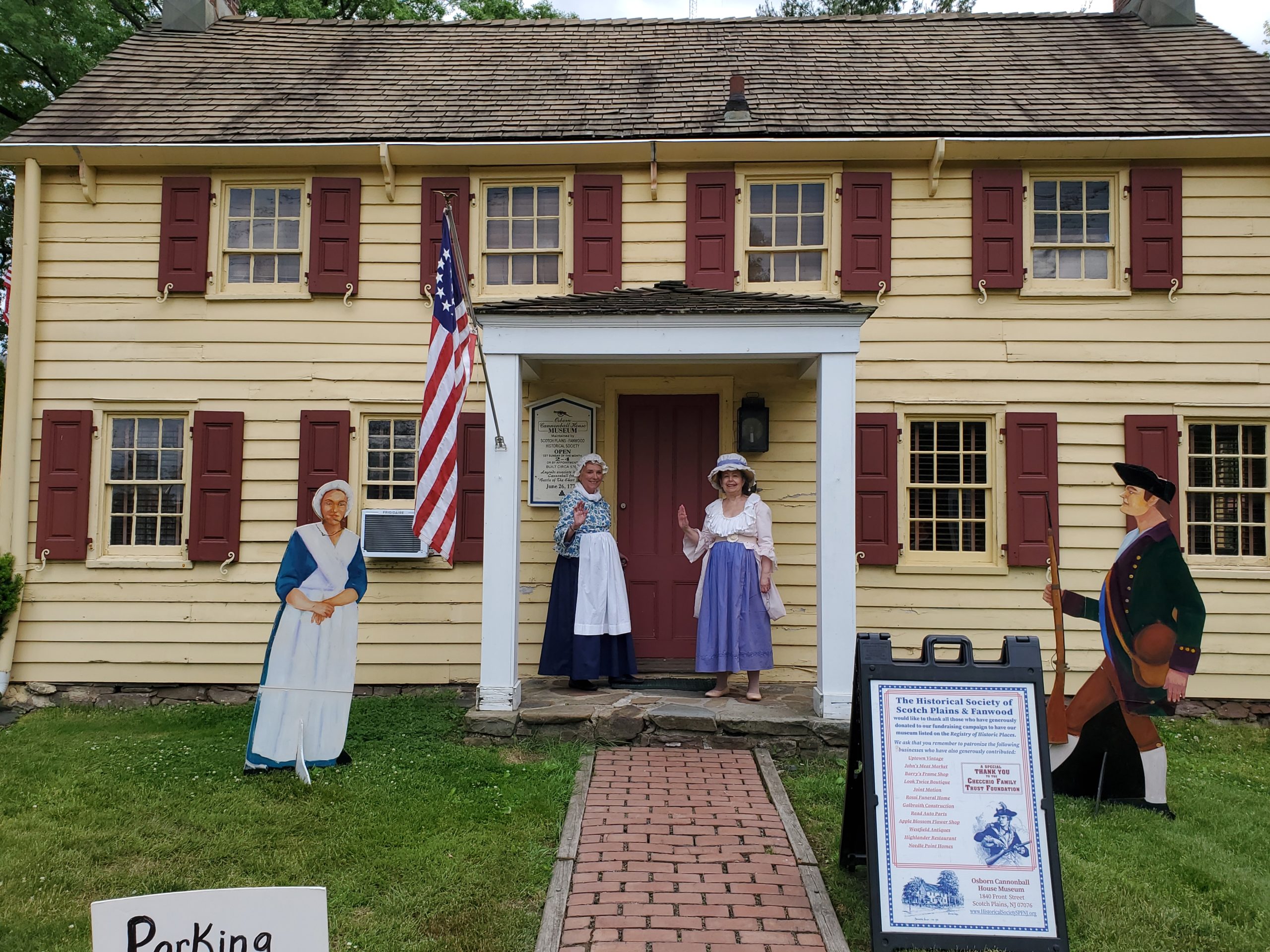 The Osborn Cannonball House Museum Front with two ladies in colonial dress welcoming visitors.